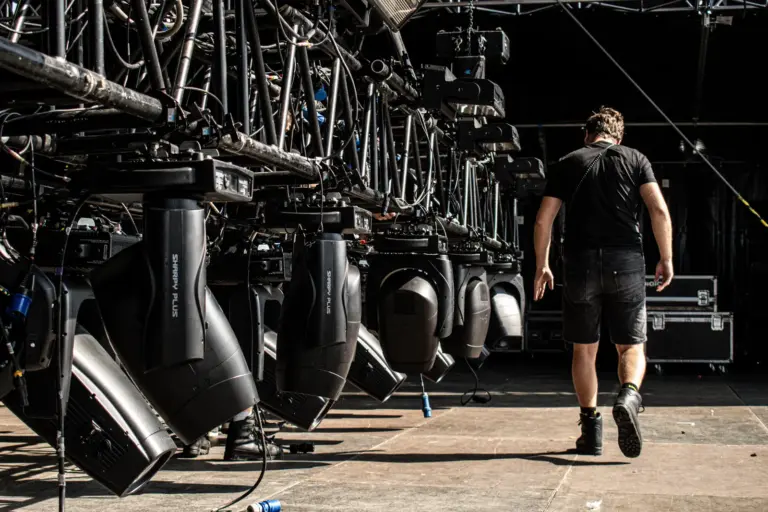 Row of moving head fixtures rigged on the Lux Expo mainstage truss during load-in