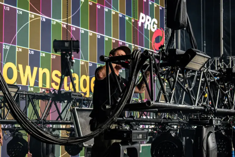 PRG technician rigging a lighting fixture in front of the mainstage LED wall at Lux Expo