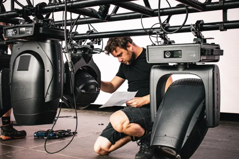 Technician checking the lighting plot against the rigged fixtures on the Lux Expo mainstage